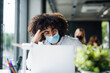 © Halfpoint - Portrait of young man with face mask back at work in office after lockdown.