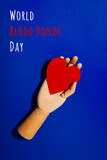 Fototapeta  - Wooden hand with big red heart in a giving gesture. World Blood Donor Day wording. Donation, help, health issues, antibody plazma concepts.