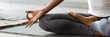 © fizkes - African woman wearing active wear do yoga practice meditating indoors, close up cropped photo lotus position. No stress, mindfulness, inner balance concept. Horizontal banner for website header design