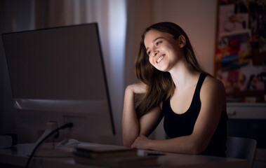 Wall Mural - Happy young girl with computer at night smiling, online dating concept.