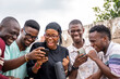 © Confidence - a group of young africans using their phones, hanging out together, students leisure on campus, viewing content on a phone together, laughing