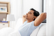© Syda Productions - people, bedtime and rest concept - indian man stretching in bed at home