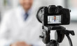 © Syda Productions - healthcare, medicine and blogging concept - happy smiling male doctor with camera recording video blog at hospital