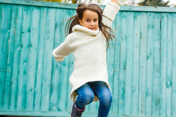 Wall Mural - Little girl in an urban setting smiles blue wooden wall