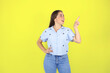 Young beautiful woman standing over yellow isolated background smiling and pointing to aside with surprise gesture.