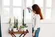 © Olga - A girl with long hair looks after flowers, watering, spraying, moisturizing, pulverizing, home, comfort, landscaping at home and office