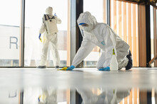 Full Length Portrait Of Two Workers Wearing Protective Suits Cleaning Surfaces Indoors During Disinfection, Copy Space