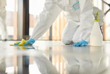Close Up Of Unrecognizable Worker Wearing Protective Suit Cleaning Floor With Chemicals During Disinfection Indoors, Copy Space