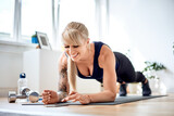 Fototapeta  - Happy athletic woman doing home workout exercises with mobile app.