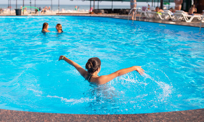 Poster - Top view unidentified pretty young girl happily splashing in blue clear water in the pool under the rays of bright sunlight. Concept of relaxation at the hotel and at sea. Advertising space