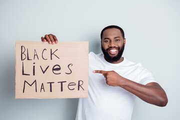 Wall Mural - We are your friends. Photo of cheerful dark skin african protester direct finger placard against black citizens lawlessness invoke police count their lives isolated grey color background