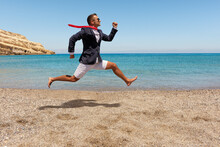 Happy Businessman Running Away From Office Work On The Beach. Summer Vacation Concept.