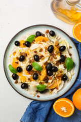 Canvas Print - Fennel, orange and olives salad, with raisins, pine nuts and basil leaves. Sicilian food. Top view.