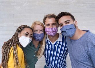 Wall Mural - Portrait of happy young people smiling - Multiracial friends wearing protective face masks - Focus on the face of the blond northern woman