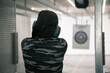 Woman aiming pistol at target in indoor firing range or shooting range