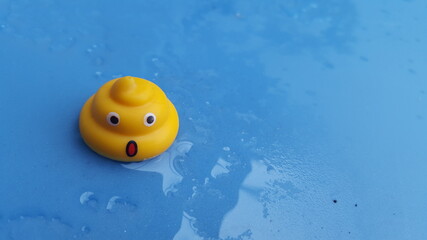 Surprised Yellow Poop Emoji Toy on Wet Blue Surface