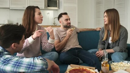 Wall Mural - A pleased relaxed friends are talking while eating snacks, pizza and drinking beer sitting in the living room at home