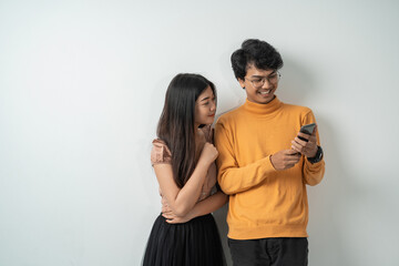 Wall Mural - Asian young couples chatting while standing on their smart phones together with isolated backgrounds