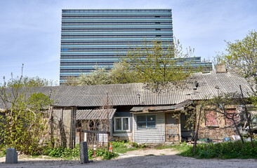 Old abandoned house and modern office building in the back