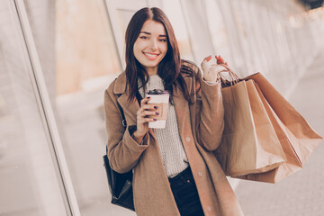 Wall Mural - Beautiful smiling young woman with shopping  bags and coffee on the street.