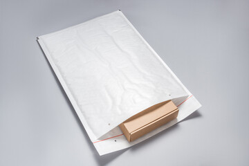 Brown cardboard box packed in white bubble envelopes on grey background