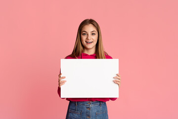 Wall Mural - Happy smiling teenage girl holding white sheet of paper in hands with empty space