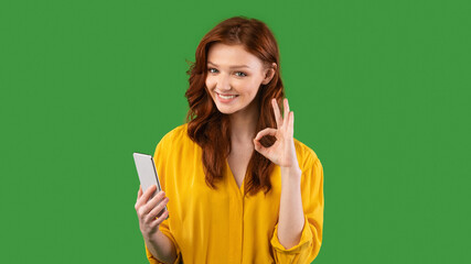 Millennial Girl Using Smartphone Gesturing Okay On Green Background, Panorama