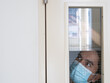 © rufous - Lonely man in medical mask looking through the window. Isolation at home for self quarantine. Concept home quarantine, prevention COVID-19. Coronavirus outbreak situation