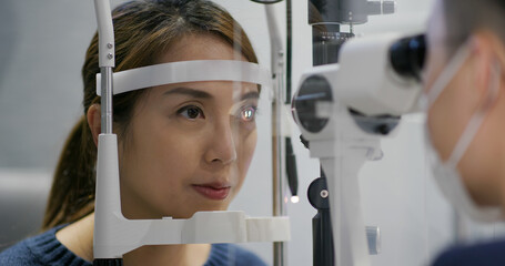 Wall Mural - Woman checks her eyes in clinic