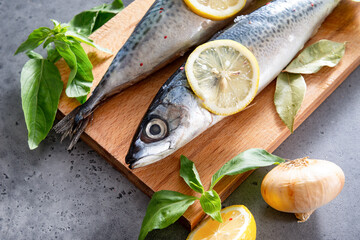 Wall Mural -  mackerel fish with spices and lemon slices on a cutting Board, Basil, onion on a gray background