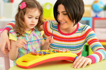 Mother with little daughter playing on musical instrument