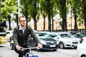 Use environmentally friendly modes of transport. Happy young man is riding a bike on the city street for gets to the office