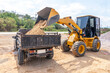 Heavy yellow Bulldozers are loading sand at the truck. Wheel loader machine unloading sand.