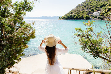 girl in summer dress and hat on beach. Long hair woman travel on vacations to beach seaside.