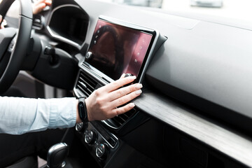 Woman twists the controls on the car radio. Listening to the radio in the car