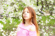 © klavdiyav - a girl in protective face mask stands near blossoming cherry tree during quarantine due to the coronavirus pandemic