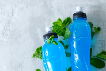 two bottles of isotonic energy drink in hand with fresh mint leaves