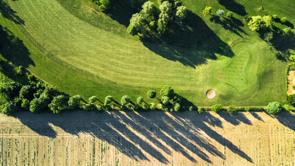 Poster - Drone view of a beautiful golf course at sunset with shadows and shapes