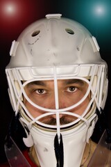 Wall Mural - Detail of a male face in a white goalie hockey mask and  colorful lights.This is a detail hockey goalie. He is concentrated on game. He has colorful lights under his head.