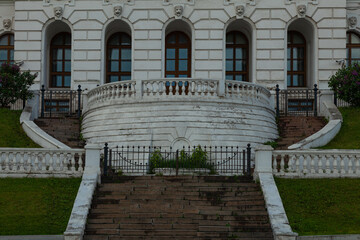 Wall Mural - Fragment of the facade of an old white building with a semicircular balcony and winding staircases