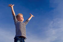 Relaxed Boy Breathing Fresh Air Raising Arms Over Blue Sky At Summer. Dreaming, Freedom And Traveling Concept.