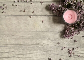 Pink candle with lilac flowers on wooden surface shot from above. Top view, flat lay, copy space.  Relaxing at home and hygge composition. Space for text. 