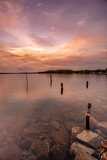 Fototapeta Mosty linowy / wiszący - sunset reflection over the lake, stones in the water