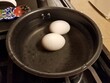 two eggs boiling in a pot of water