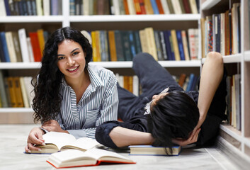 Wall Mural - Two multicultural students lying on floor at campus library