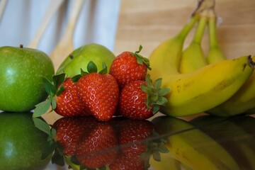 Poster - Closeup shot of fresh strawberries, bananas and apples on the table