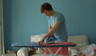 Young man ironing clothes