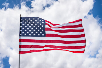 Close up of beautifully waving star and striped American flag; Concept for Memorial Day or 4th of July; White clouds background