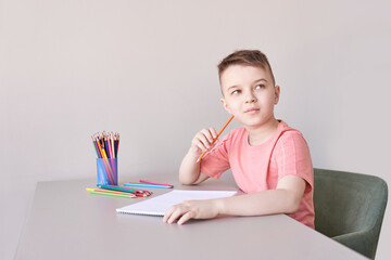 Little boy drawing. Closed Locking Exercise. Homemade routine. School lessons. Write pencil on piece of paper. Home study. Elementary preschool. Male kid student. Thinking or dreaming