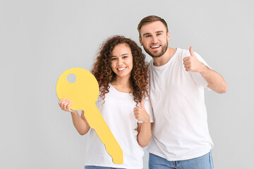 Canvas Print - Happy young couple with big paper key on grey background